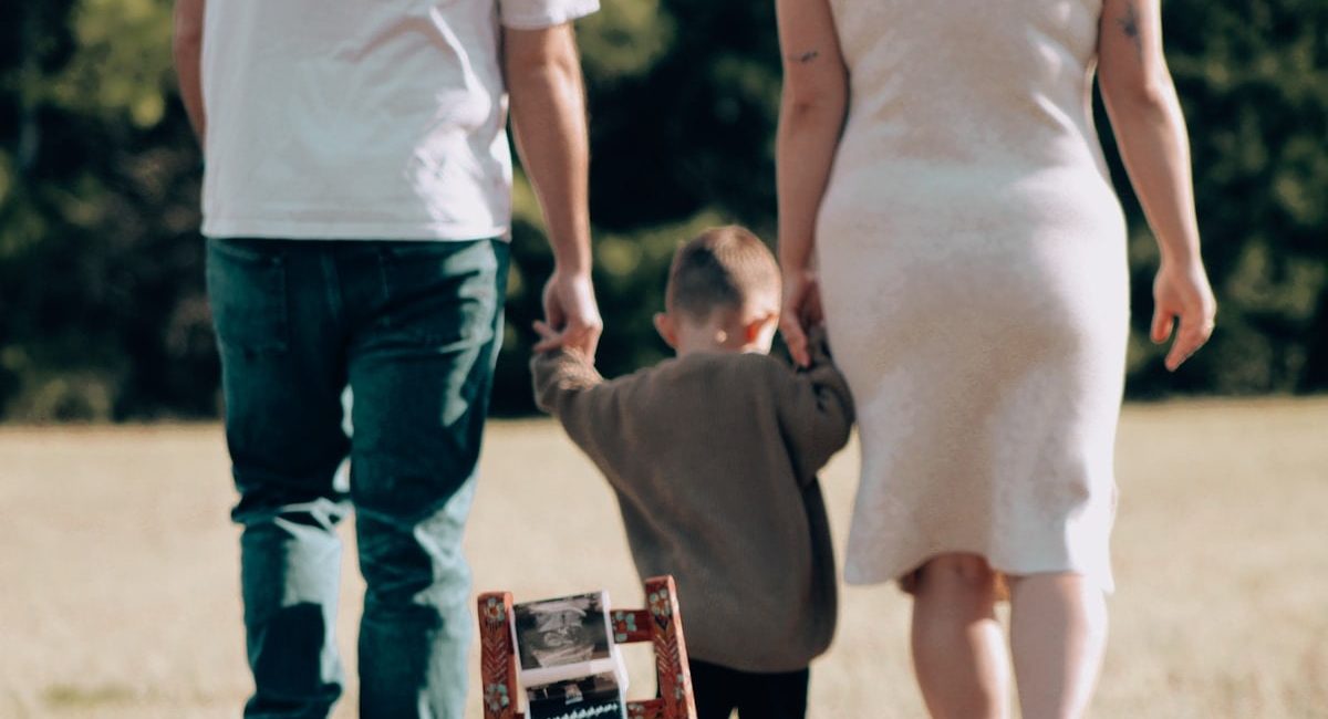 Family holds hands while looking at a baby ultrasound.